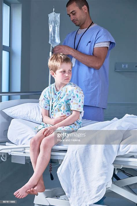Male Nurse Adjusting Boy Patients Intravenous Drip In Hospital