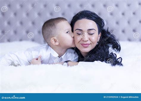 Mothers Day Mom And Son Lie On The Bed Son Kisses Mom On The Cheek