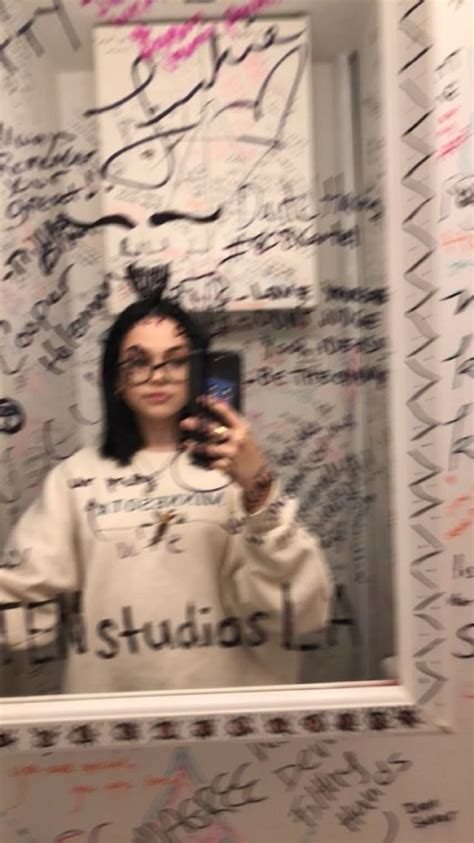 A Woman Taking A Selfie In Front Of A Mirror With Writing All Over It