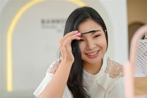 Attractive Asian Woman Applying An Eyebrow Mascara Doing Makeup Stock