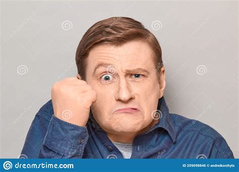 Portrait Of Angry Disgruntled Man Shaking Fist In Threatening Gesture