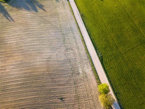 Aerial View Of Dirt Road Separating Green Meadow And Brown Agricultural