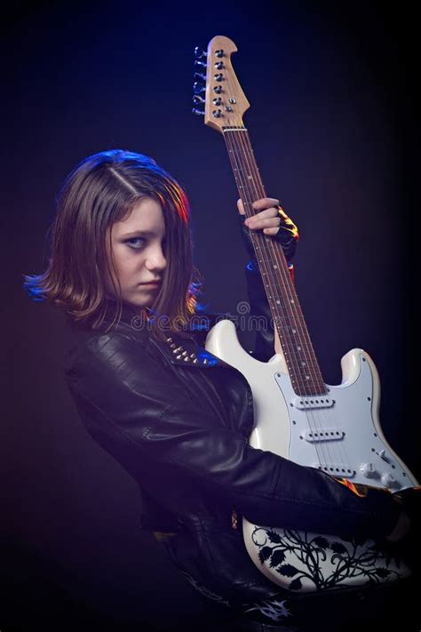 Young Attractive Rock Girl Playing Electric Guitar Against Dark