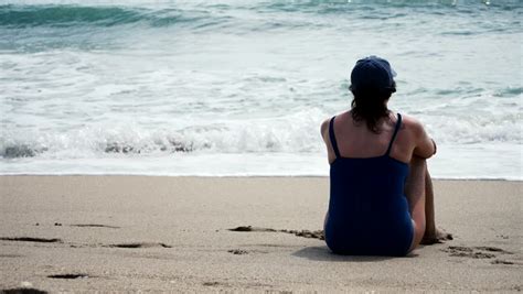 Black Woman Sits Back Relaxing On The Beach Looking Out Into The Ocean