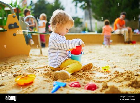 Adorable Little Girl On Playground In Sandpit Toddler Playing With