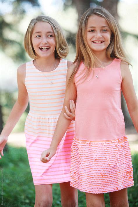 Happy Fraternal Twin Sisters Wearing Dresses Laughing Stocksy United