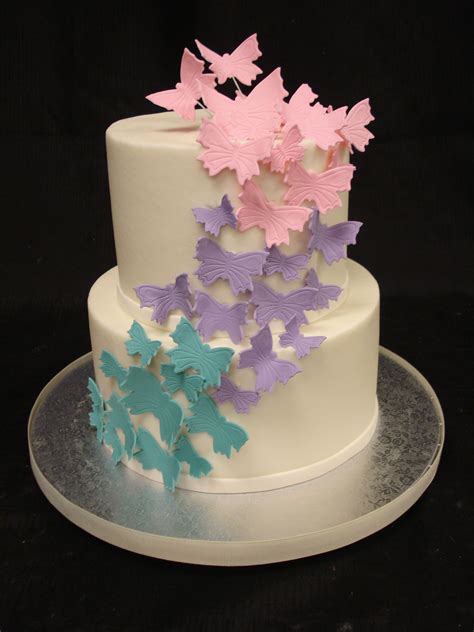 A Three Tiered White Cake With Butterflies On The Icing And Fondant