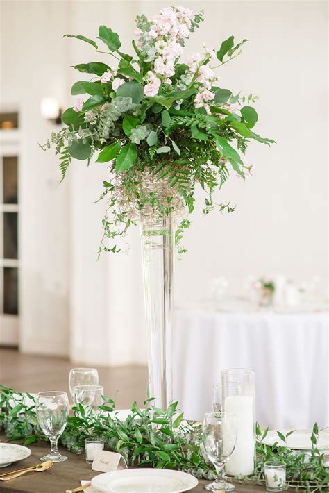 This Floral And Greenery Tall Vased Wedding Centerpiece With Candles