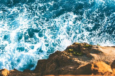 Top View Of Sea Waves Hitting Rocks On The Beach With Turquoise Blue