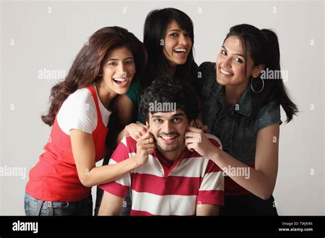Three Women Pinching Cheeks Of A Man And Smiling Stock Photo Alamy