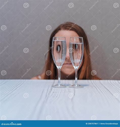 crazy portrait of a woman looks through wine glasses big funny eyes optical distortion through