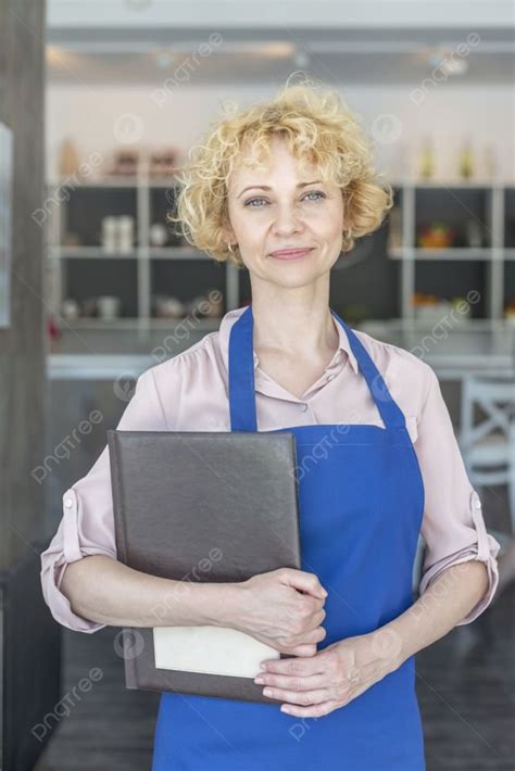 Portrait Of Confident Mature Waitress Holding Menu At Restaurant Photo Background And Picture
