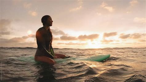 Surfer Girl Sitting On Surfboard At Sunset Waiting For Waves Del Colaborador De Stocksy C6