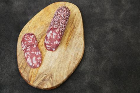 Salami Sausage And Slice Of Sausage On Wooden Board On A Black