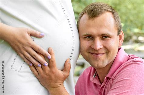 Handsome Man Is Listening To His Beautiful Pregnant Wifes Tummy Belly And Smiling Husband