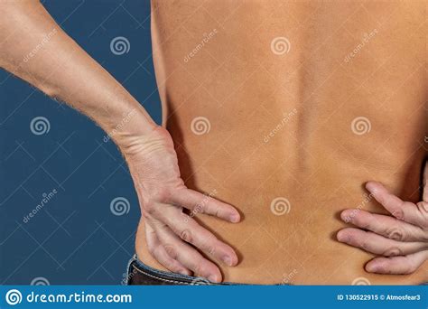 Man Holding His Painful Inflamed Loin On Blue Background Health Care