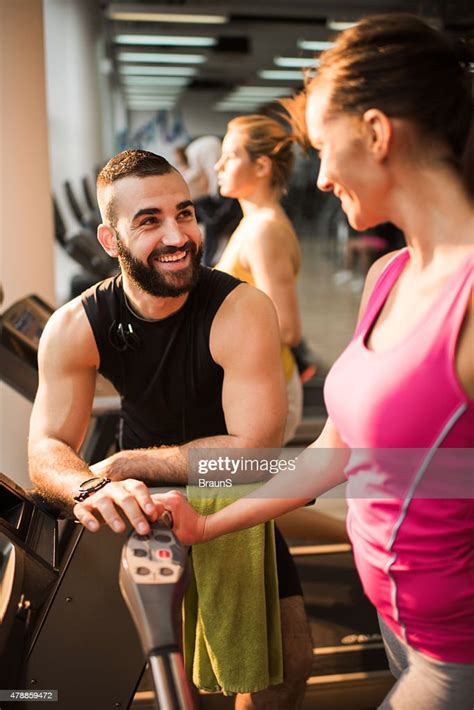 Smiling Coach Assisting Young Woman In A Gym High Res Stock Photo