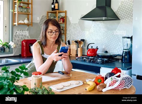 Frau ihr gesundes Frühstück genießt und zu Hause auf ihrem Smartphone nachcheckt Brunch