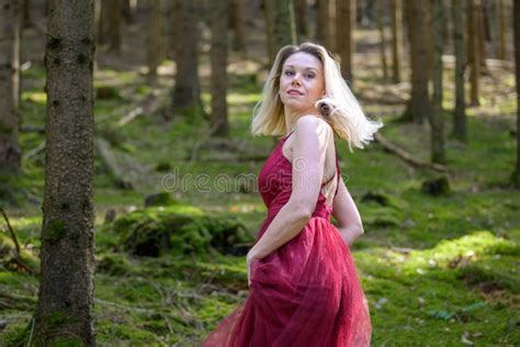 Pretty Blond Woman Turning Around Against Trees In Woods Stock Photo