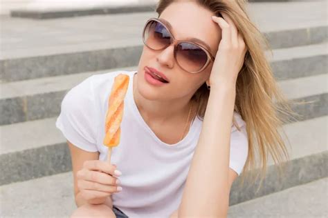 kaunis nuori seksikäs tyttö aurinkolasit syö jäätelöä tikkailla ja nuolee pulleat huulet kirkas