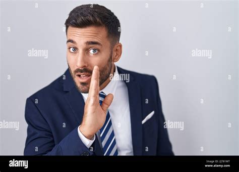 Handsome Hispanic Man Wearing Suit And Tie Hand On Mouth Telling Secret Rumor Whispering
