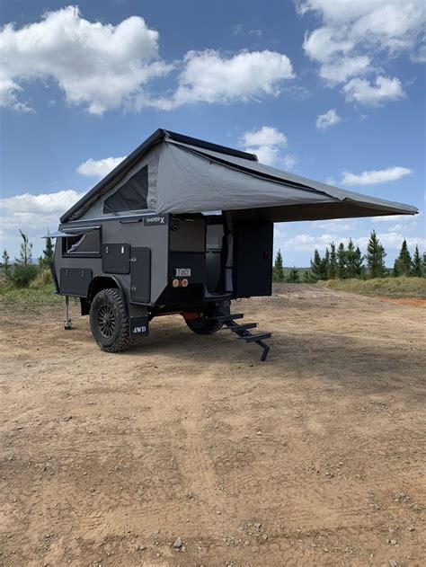 An Off Road Camper Trailer Sits In The Middle Of A Dirt Field