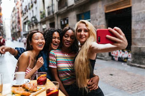 Multi Racial Friends Taking A Selfie With Cellphone In A Restaur Del Colaborador De Stocksy