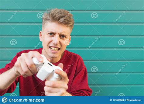 Concentrated Teenager In Red Svyatyshirt And Joysticks In His Hands