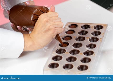 Chocolatier Pouring Caramel Filling Into Chocolate Mold Preparing