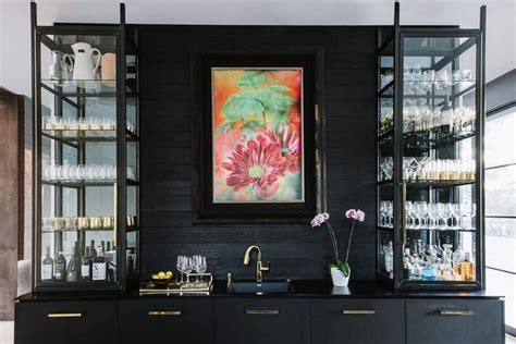 A Painting Hangs On The Wall Next To A Bar With Wine Glasses And Vases