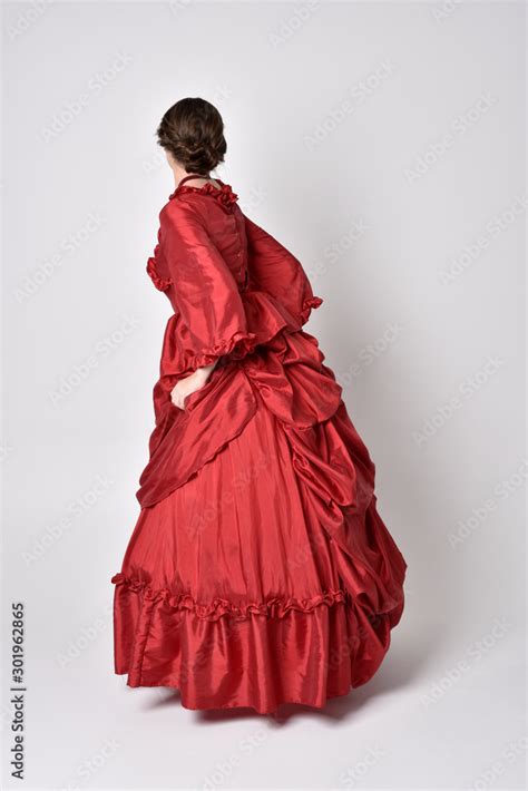 Full Length Portrait Of A Brunette Girl Wearing A Red Silk Victorian