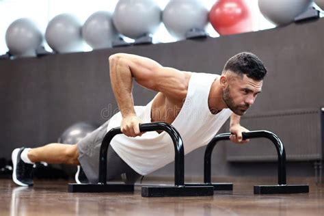 Fit And Muscular Man Doing Horizontal Push Ups With Bars In Gym Stock