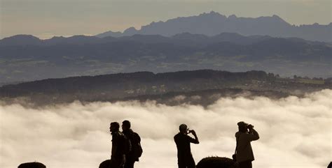 .or explore the rest of europe? People look over the high fog covered landscape towards the eastern Swiss Alps from a look-out ...