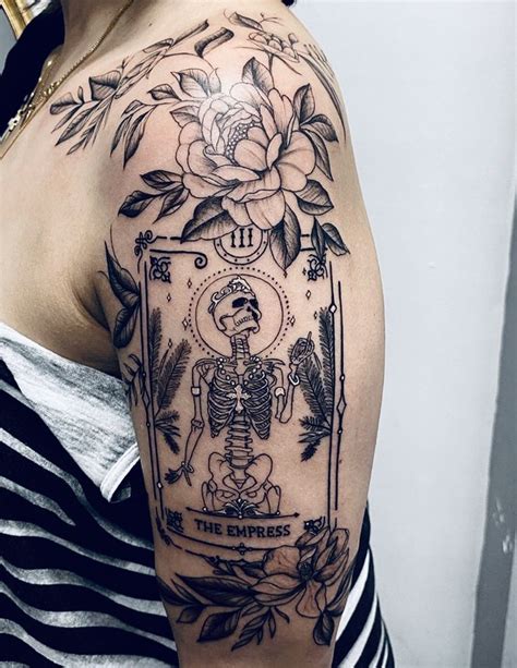 A Womans Arm With A Skeleton And Flower Tattoo On The Left Side Of Her