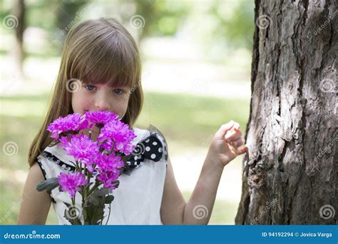Śliczna Mała Dziewczynka Trzyma Bukiet Kwiaty W Ręce I Cieszy Się Zdjęcie Stock Obraz Złożonej
