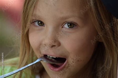 Cute Little Girl Eating Of An Ice Cream Spoon With A Dirty Face Stock