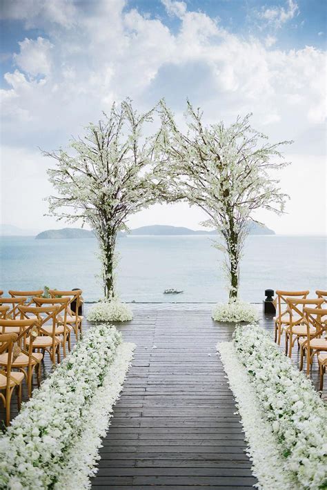 Wedding Ceremony Featuring An Arch Made From Trees Of White Florals