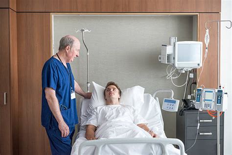 Best Young Man Lying In Hospital Bed With Senior Doctor Stock Photos
