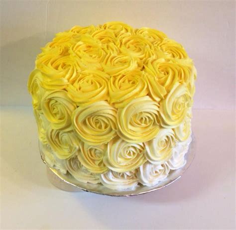 A Yellow Cake With White Frosting Roses On It