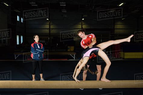 Female Gymnast Practicing On Balance Beam With Coach Stock Photo Dissolve