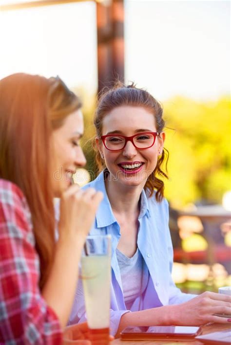 Two Smiling Female Friends Talking Drinking Coffee Outdoors In The