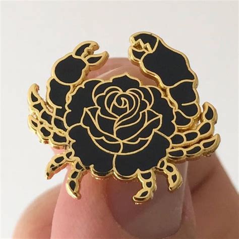 A Close Up Of A Persons Hand Holding A Black And Gold Brooch