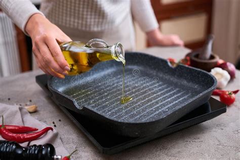 Housewife Pouring Olive Oil On Hot Frying Pan At Domestic Kitchen Stock