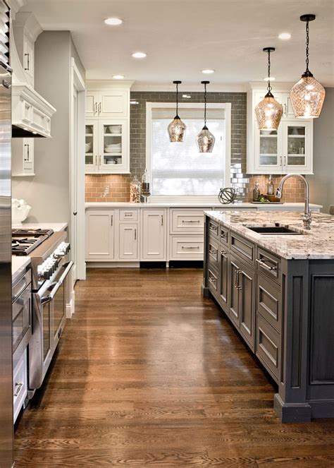 White large luxury modern kitchen with dark floor. Gray island and white cabinets. Granite top. White oak ...