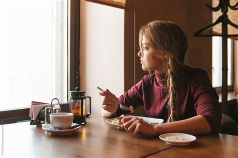 Thoughtful Beautiful Woman Eating In Restaurant Del Colaborador De Stocksy Danil Nevsky
