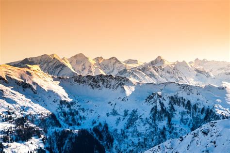 Winter Snowy Peaks Of Alps Mountain Panorama Illuminated By Sunset At