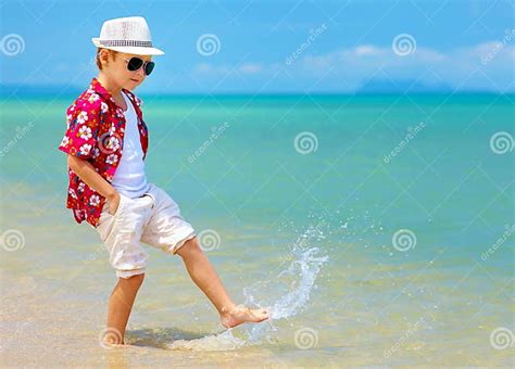 Happy Fashionable Kid Boy Walking In Surf On Tropical Beach Stock Photo