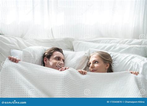 Top View Of Beautiful Young Caucasian Couple Hiding Under Blanket And Looking At Each Other With