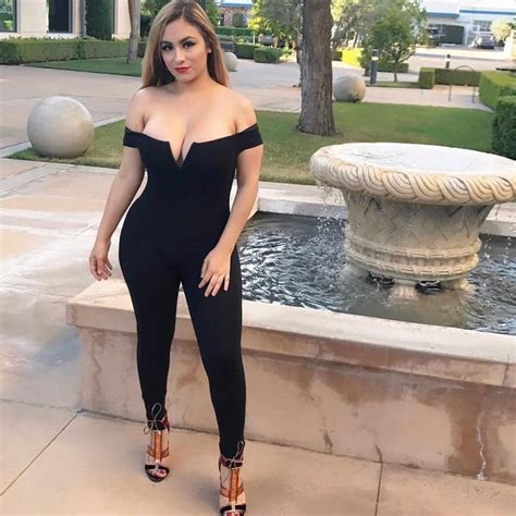 A Woman Standing In Front Of A Fountain Wearing High Heels And A Black Bodysuit