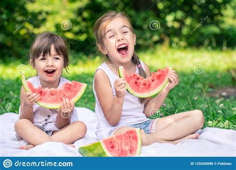 Two Little Cute Girls Eating Watermelon Outdoors Stock